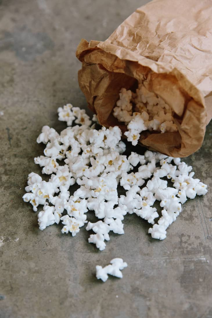 Popcorn in and outside of a plain brown paper lunch bag