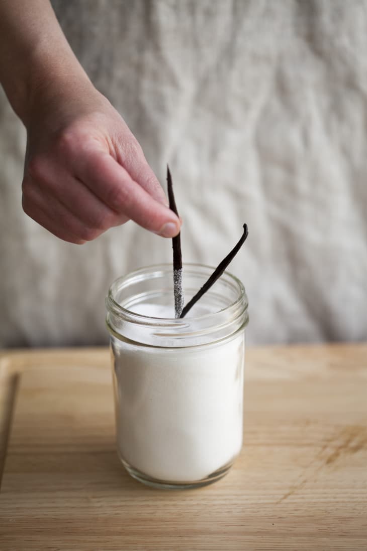 Milk in a small mason jar is infused with scraped-out pods of vanilla bean