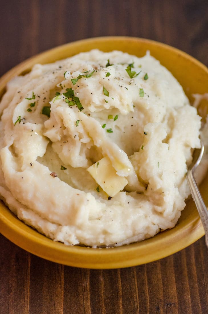 Mashed potatoes with a pat of butter in a yellow bowl.