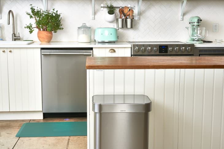 A modern rustic kitchen with an island and stainless steel trash can