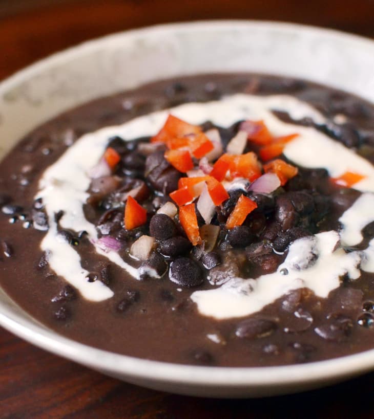 Cuban black bean soup, garnished with sour cream, chopped onions and bell peppers, in a bowl
