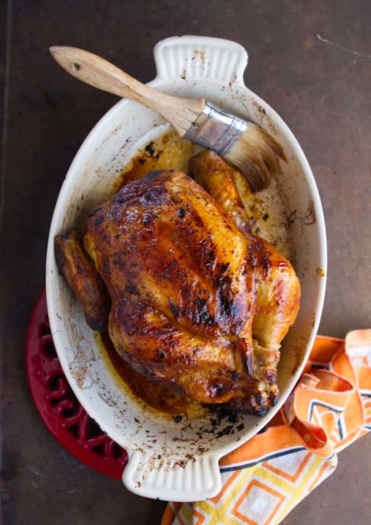 Roasted chicken on a baking dish, with a basting brush