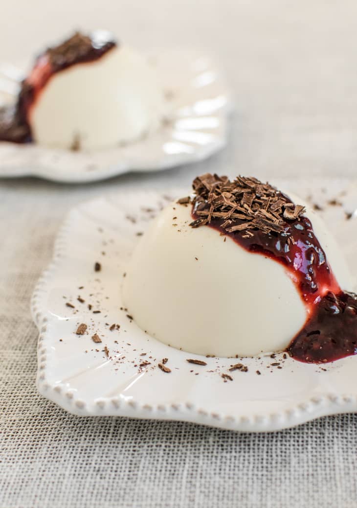 Panna cotta topped with fruit jam and chocolate shavings on a small plate