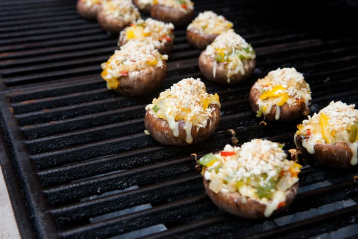 Mushrooms stuffed with cheese, diced yellow bell peppers, sweet onions, and Panko, are on a griller