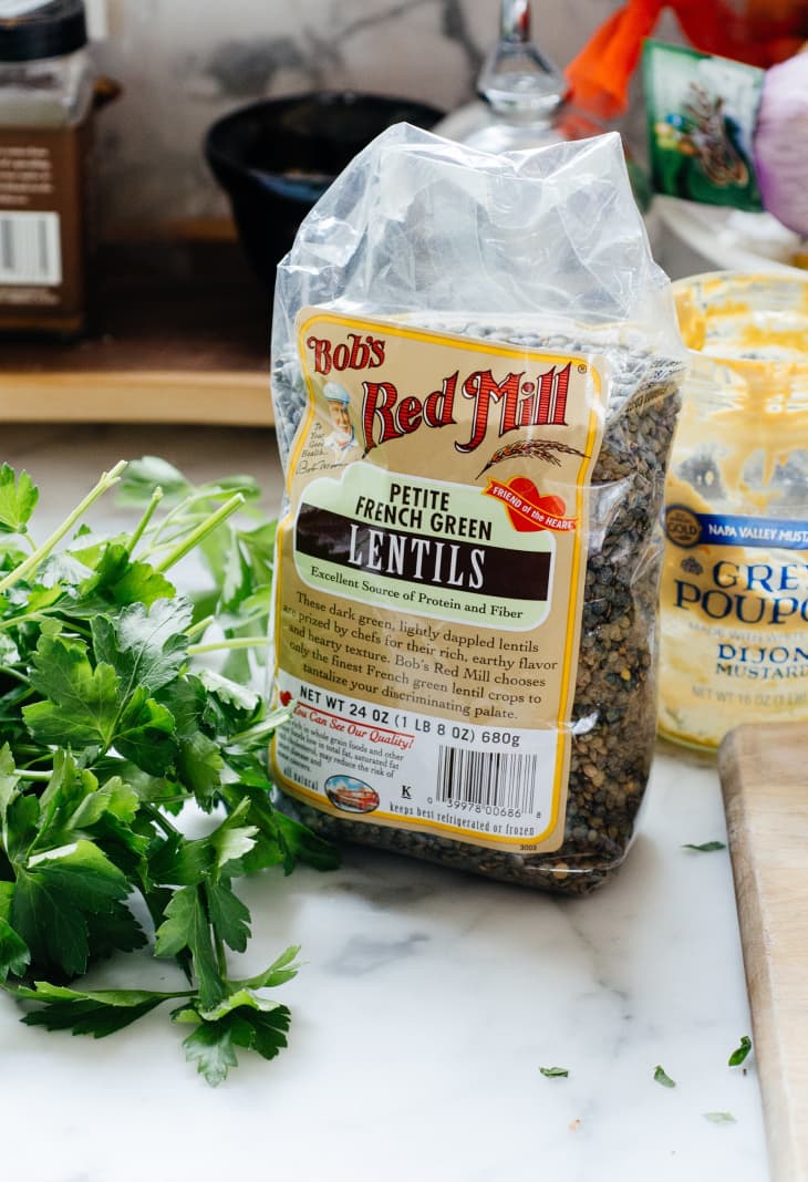 A package of Bob's Red Mill petite French green lentils and fresh parsley beside it