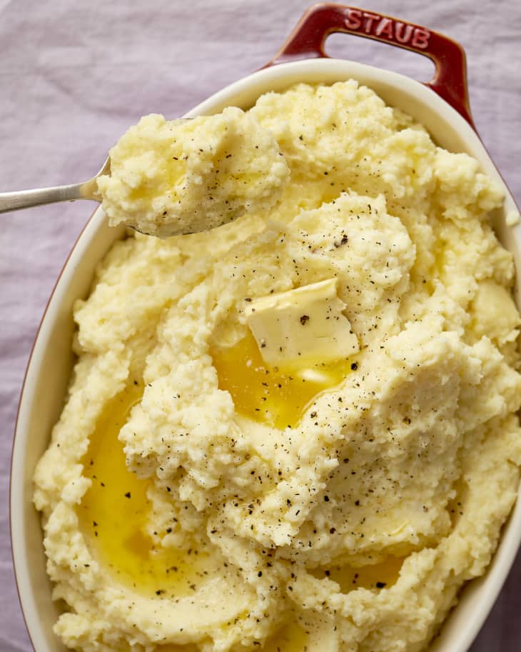 Baking dish filled with mashed potatoes with a melting pat of butter