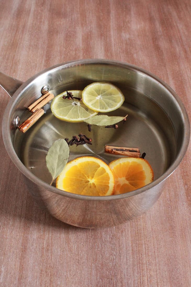 Potpourri ingredients (citrus fruit slices, pay leaves, cinnamon sticks, and cloves) in a pot of water