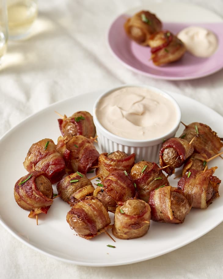 Bacon-wrapped potato bites, served with spicy sour cream dipping sauce, on a plate