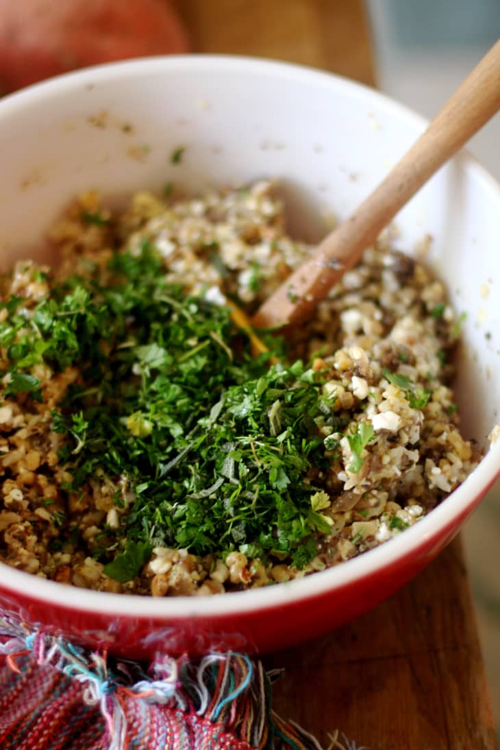 A mixture of brown rice, chopped mushrooms, nuts, and fresh herbs in a bowl