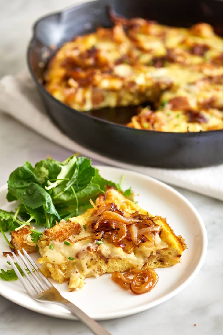 A slice of French onion frittata served with greens on a plate