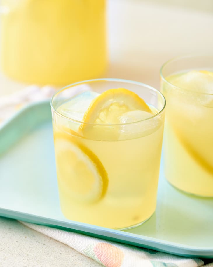 Glass tumblers filled with lemonade, ice, and lemon slices