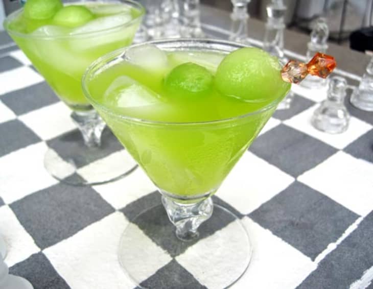 A glass of melon ball cocktail, garnished with ball-shaped melon