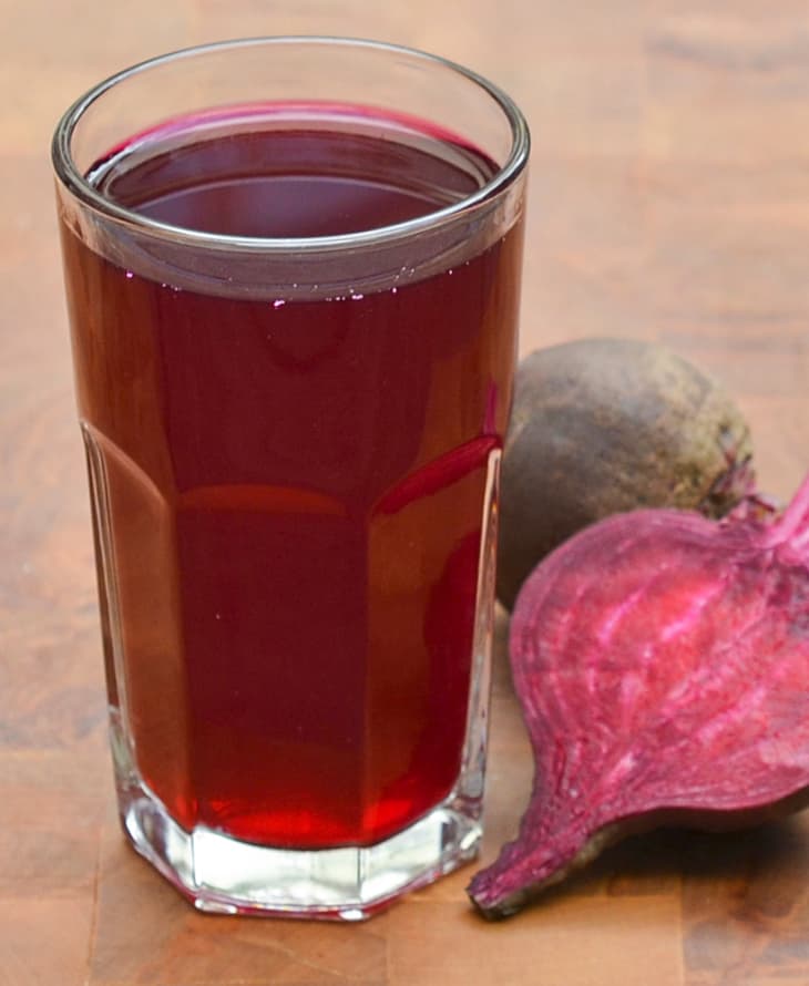 A glass of beet kvass with raw beets on the side