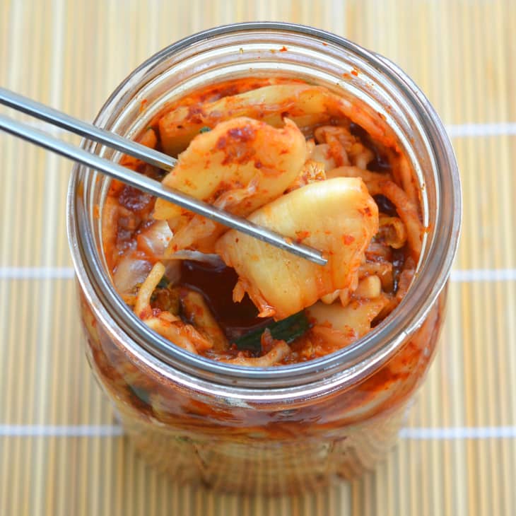 Jar of homemade kimchi, chopsticks removing a piece