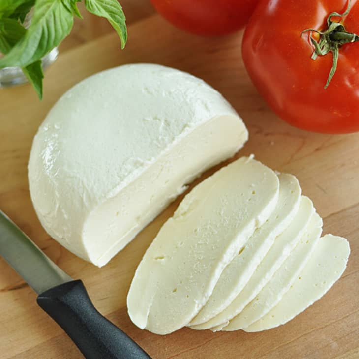 Slices of fresh mozzarella with tomatoes and basil beside it