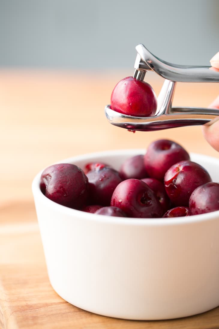 Using a cherry pitter to prepare fruit for making clafoutis