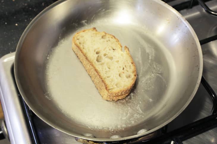 Slice of peasant bread heating with butter in a skillet, stovetop