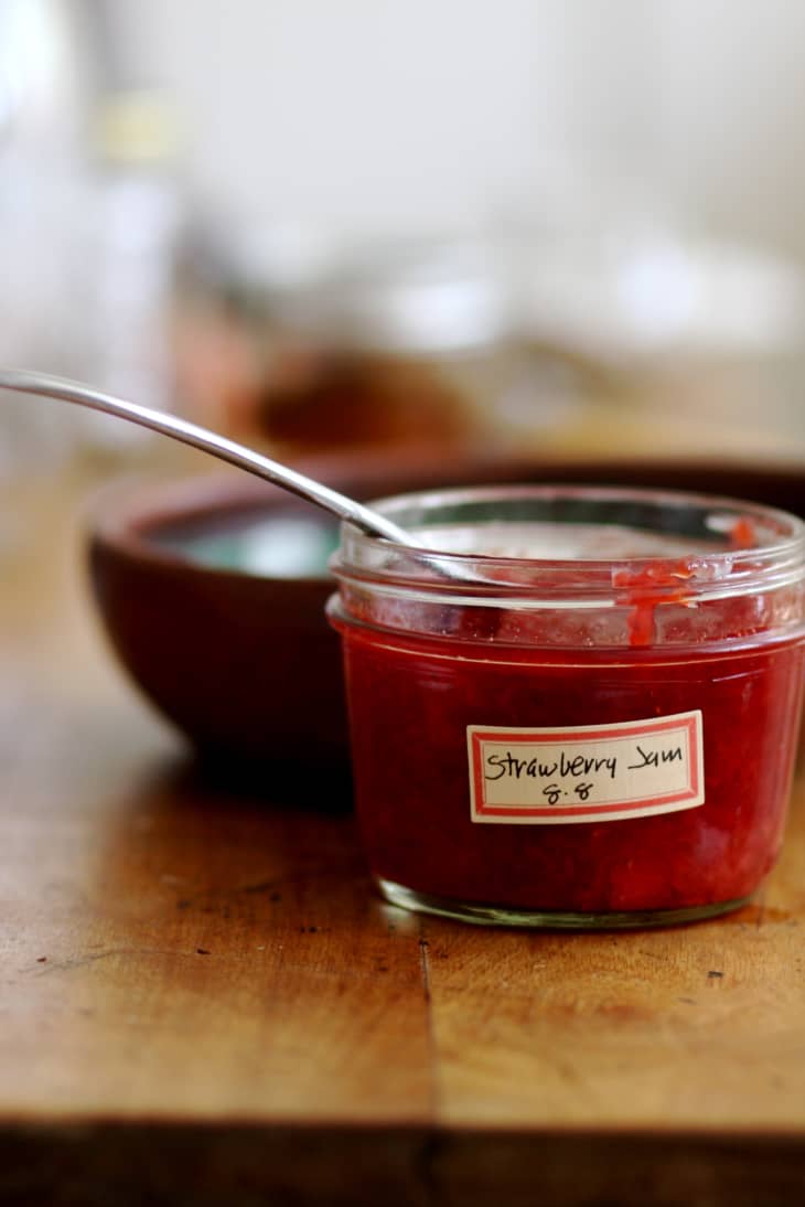 Strawberry jam in a small jar with a spoon inside
