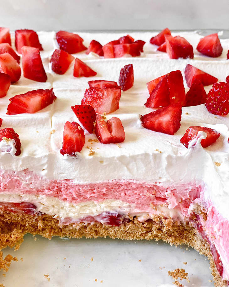 Strawberry delight layered dessert on counter with one slice out
