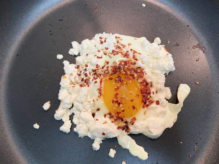 feta fried egg, cooking in skillet, chili flakes added