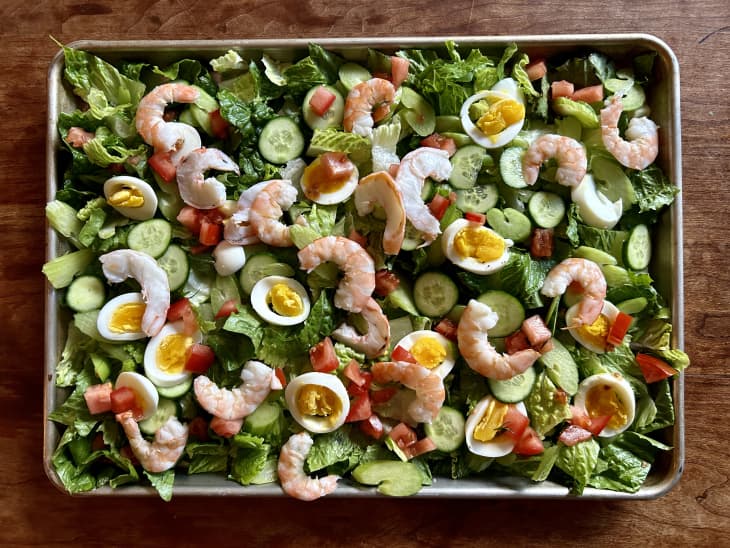 sheet pan full of cut lettuce, cucumbers, celery, hard boiled jammy eggs, shrimp