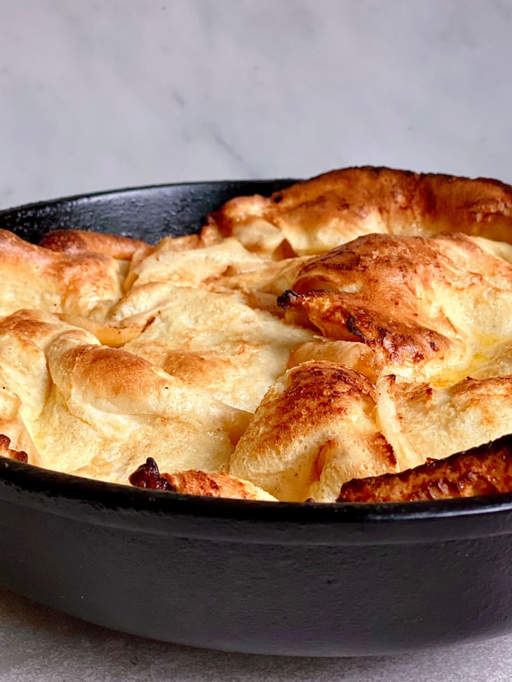 fluffy light german pancake in cast iron skillet with browned edges and curly ends