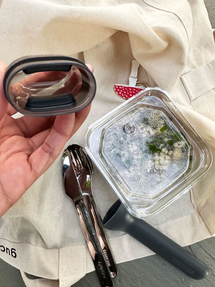 Someone holding lid for Zoku's reusable utensils while prepared salad sits on the side.
