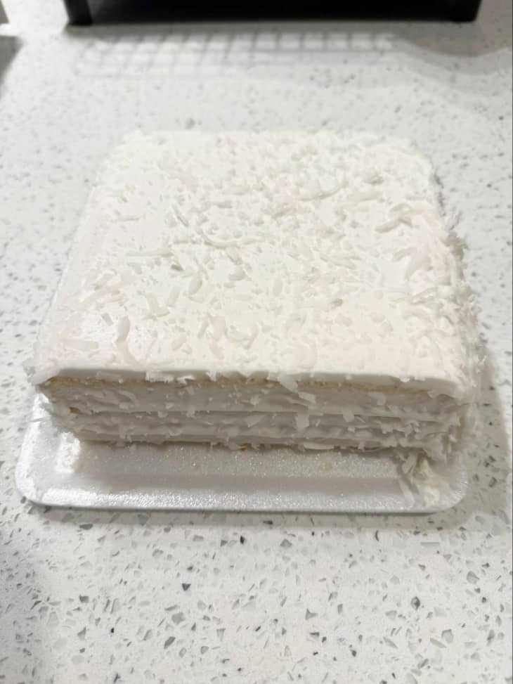 white coconut layer cake on styrofoam plate