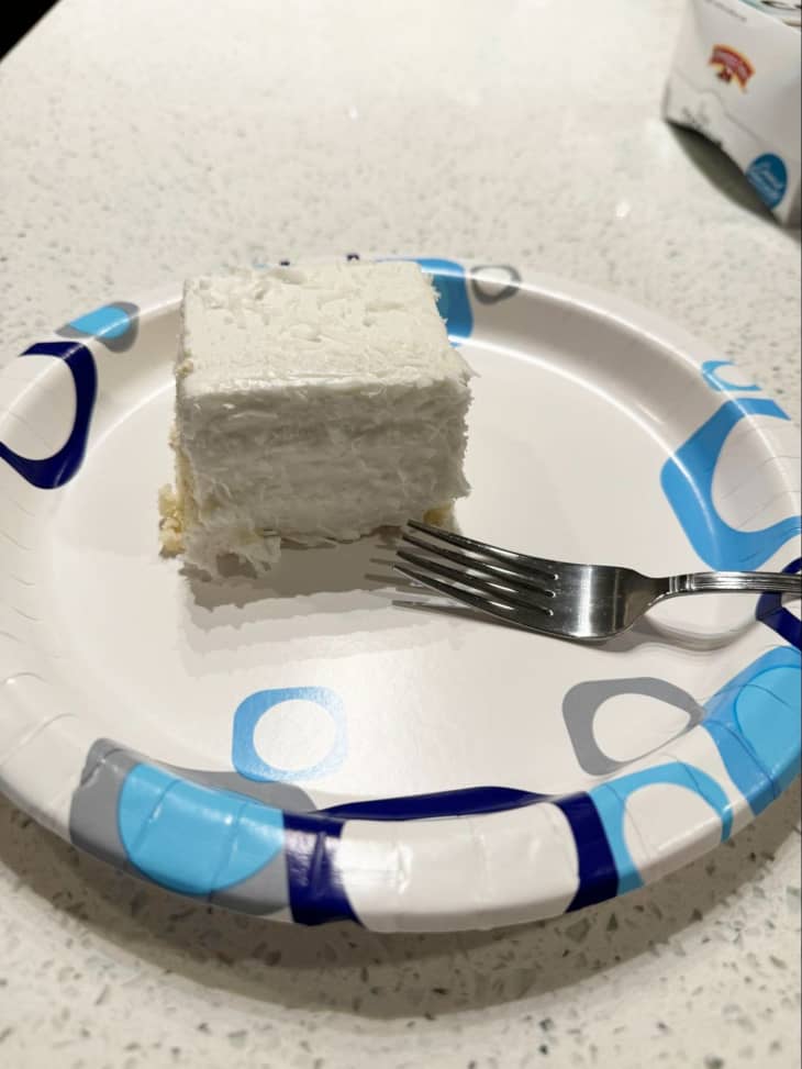 slice of layered white coconut cake on plate