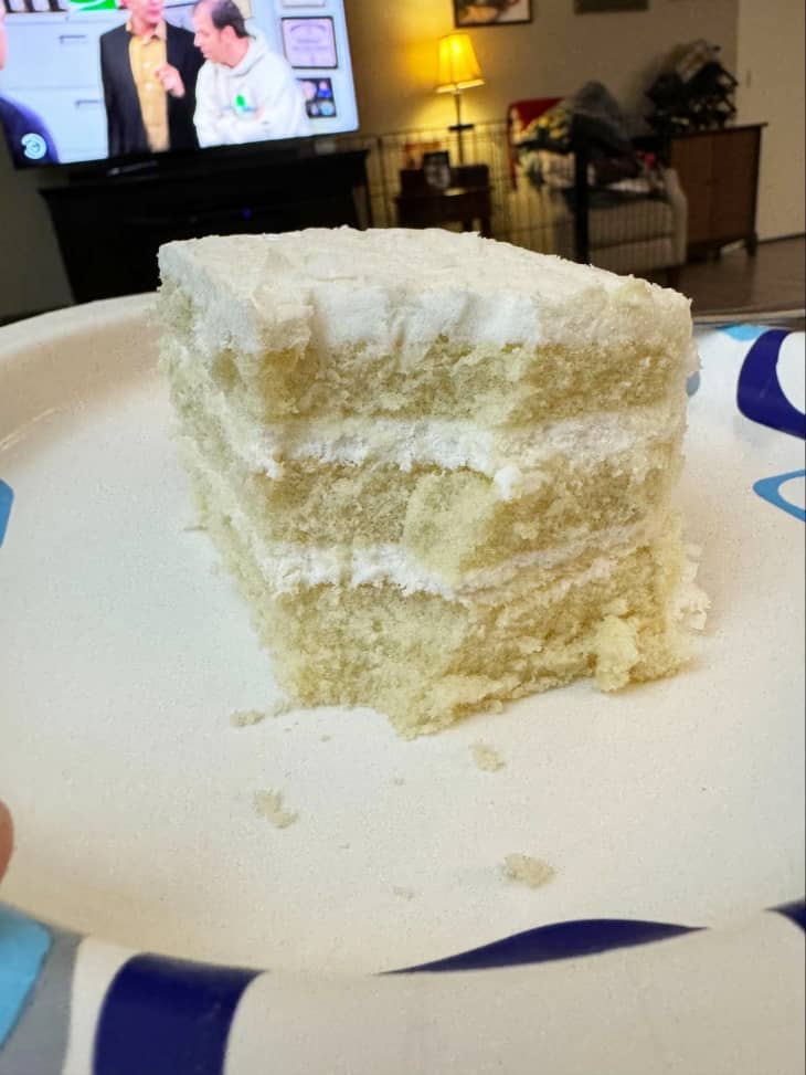 slice of layered white coconut cake on plate with bite taken out