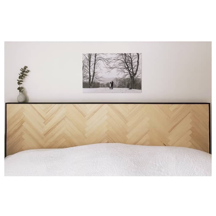 A white bed with herringbone wood patterns on the headboard.