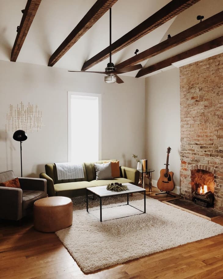 a rustic Nashville living room has rustic exposed beams and a brick fireplace