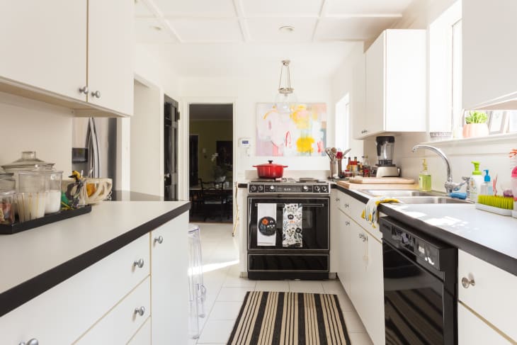 A white and black kitchen with a striped rug.