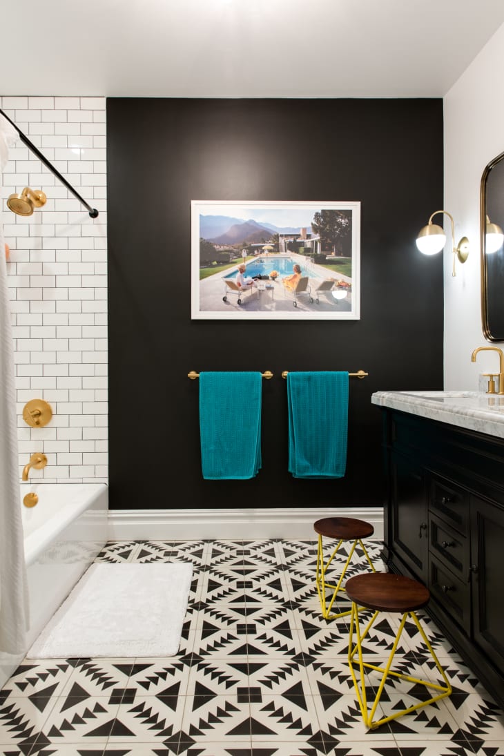A bathroom with a black accent wall and blue towels.
