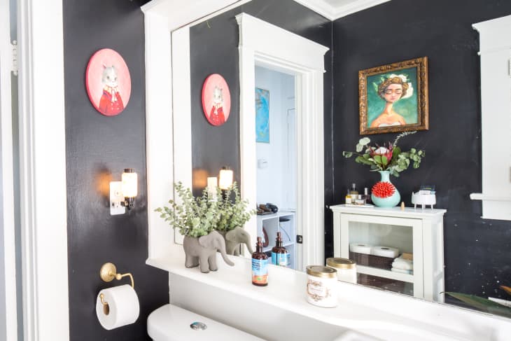A bathroom with black walls and paintings.