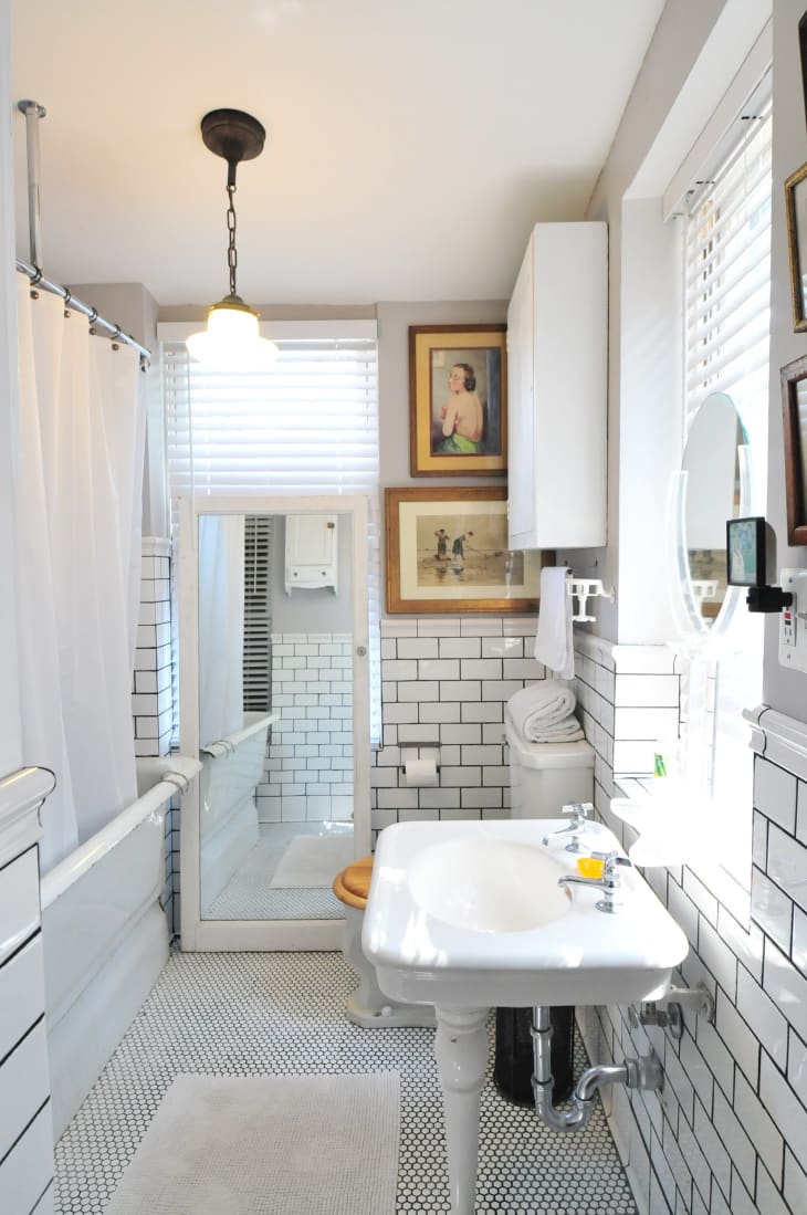 A bathroom with white subway tile on the bottom half of the wall.