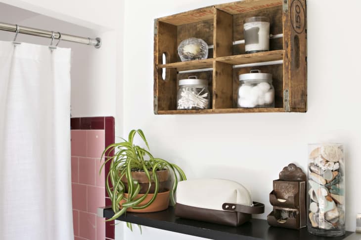A vintage wooden crate used as a display shelf in a bathroom.