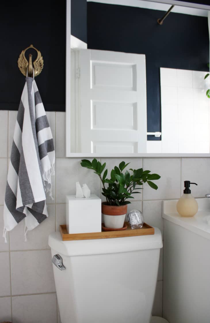 A small wooden tray is placed on top of the toilet for storage.