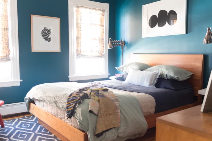 Bed with gray sheets in a room painted royal blue