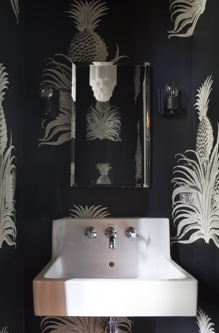 Half bath with black and silver pineapple print wallpaper