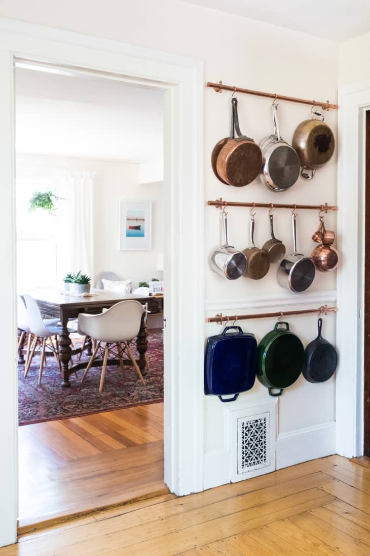A kitchen wall decorated with hanging pots and pans