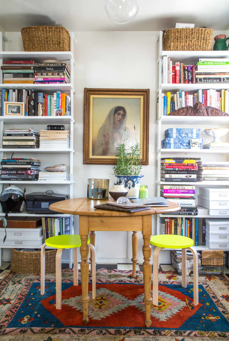 A painting between two bookshelves with a kitchen table in the foreground.