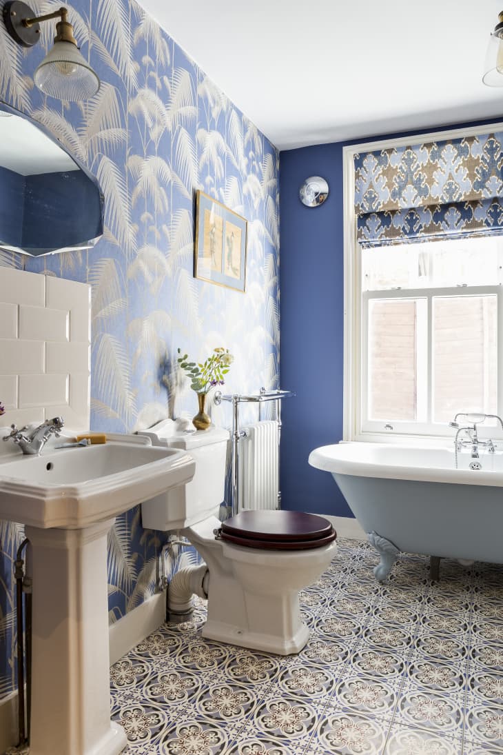 A colorful bathroom with a blue tub, blue walls, and brown patterned flooring
