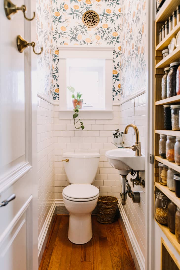 A tiny sink is mounted on the side of this small powder room.