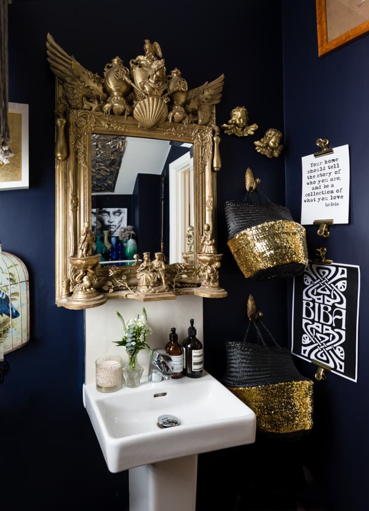 A bathroom with an elaborate, guilded mirror.