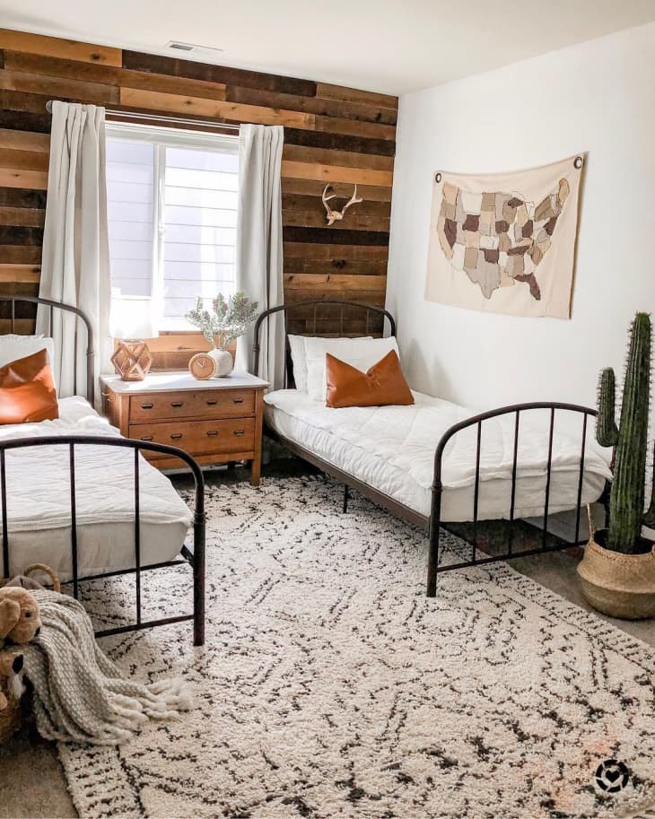 twin beds in white and a wooden palette accent wall in a rustic bedroom