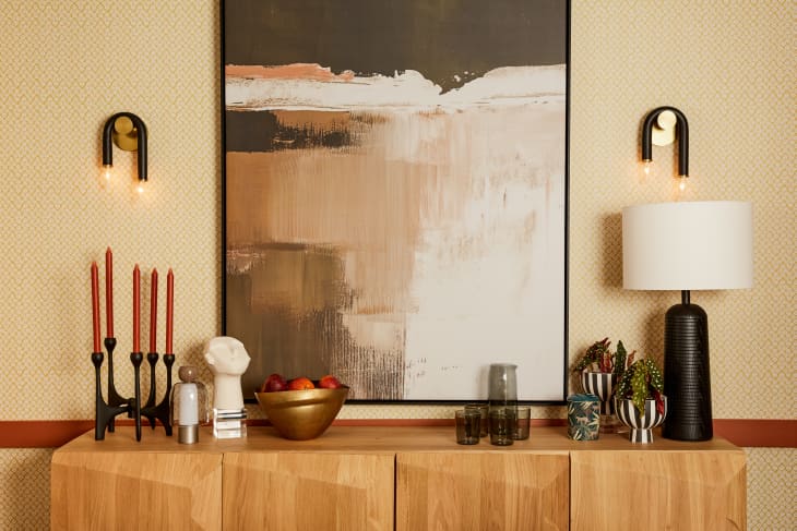 wood credenza with candles, lamp, l'objets. abstract print on wall behind