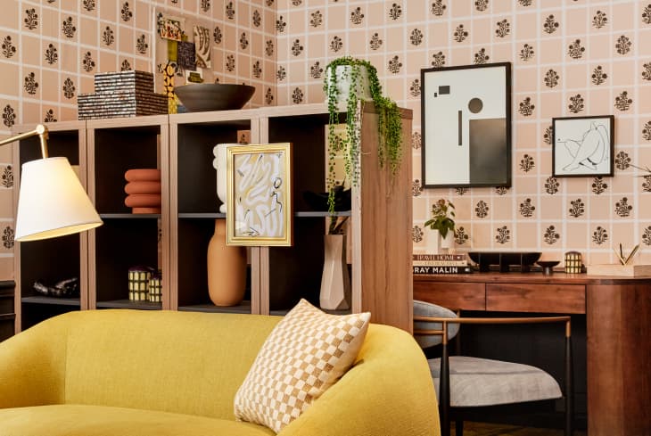 room with gold sofa, custom printed wallpaper, framed art prints, bookshelves with objets