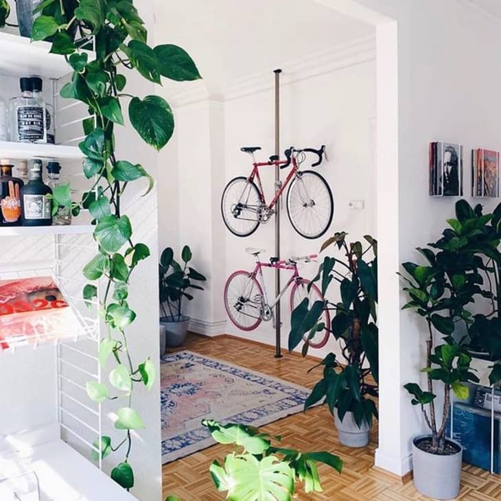 a small apartment has a pole that mounts two bicycles