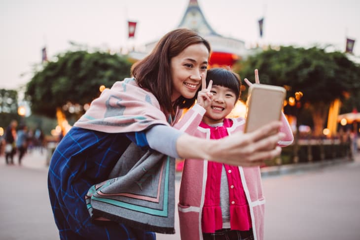 Mom taking selfies with her daughter in the theme park.